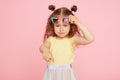 Portrait of surprised cute little toddler girl  in sunglasses over pink background.  Child model Royalty Free Stock Photo