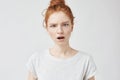 Portrait of surprised displeased freckled girl looking at camera. Copy space. Isolated on white.