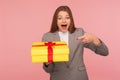 Portrait of surprised elegant businesswoman in suit jacket pointing at unexpected present and shouting in amazement