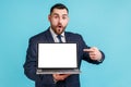 Portrait of surprised excited man with beard in suit pointing finger at empty laptop display looking Royalty Free Stock Photo