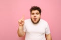 Portrait of surprised fat man in white t-shirt and with beard on pink background, looks into camera with shocked face, and shows Royalty Free Stock Photo