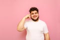 Portrait of surprised fat man in white t-shirt stands on pink background, looks into camera with shocked face and points finger at Royalty Free Stock Photo