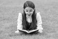 Portrait of surprised girl reading book lying on grass, reading. Teen girl reading outdoors Royalty Free Stock Photo