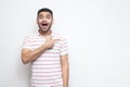 Portrait of surprised handsome bearded young man in striped t-shirt standing, looking at camera with amazed face and pointing at Royalty Free Stock Photo