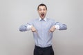 Portrait of surprised handsome bristle businessman in classic blue shirt standing and pointing at down copyspace and looking at Royalty Free Stock Photo