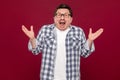 Portrait of surprised handsome middle aged business man in casual checkered shirt and eyeglasses standing with raised arms and Royalty Free Stock Photo