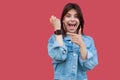 Portrait of surprised happy beautiful brunette young woman in denim casual style standing showing and pointing at screen of her Royalty Free Stock Photo