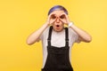 Portrait of surprised hipster girl holding hands in binoculars gesture and looking with amazement. studio shot Royalty Free Stock Photo