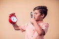 A portrait of surprised boy looking through magnifier at alarm clock. Children and time management concept Royalty Free Stock Photo