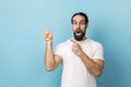 Surprised man showing copy space for commercial text, blank wall with idea presentation. Royalty Free Stock Photo