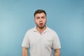 Portrait of a surprised man in a white T-shirt on a blue background looking at the camera with a shocked and scared face Royalty Free Stock Photo