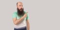 Portrait of surprised middle aged bald man with long beard in light t-shirt standing, looking with shocked face and pointing at Royalty Free Stock Photo