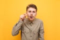 Portrait of surprised nerd on yellow background, takes off glasses and with shocked face looks into camera. A man with poor