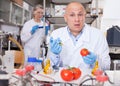 Surprised scientist injecting chemicals into tomato