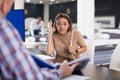 Shocked Latina talking with salesman, looking at prices in furniture store