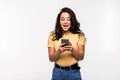 Portrait of a surprised attractive woman holding mobile phone and looking at camera isolated over white background Royalty Free Stock Photo