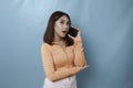 A portrait of a surprised young Asian woman having a phone call,  on blue background Royalty Free Stock Photo
