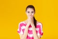 Portrait of surprised young brunette woman in pink shirt on yellow background. girl looks at camera Royalty Free Stock Photo