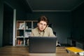 Portrait of a surprised young man doing business from home, using a laptop and making calls at work, looking at camera with Royalty Free Stock Photo