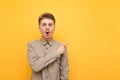 Portrait of surprised young man in glasses and mustache on yellow background, looks into camera with shocked face and shows thumbs Royalty Free Stock Photo