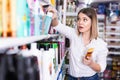 Portrait of surprised young woman near shelves with hair care products at cosmetics store Royalty Free Stock Photo