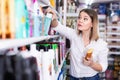Portrait of surprised young woman near shelves with hair care products at cosmetics store Royalty Free Stock Photo