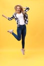 Portrait of surprised young woman in black pants jumping in front of yellow wall. Indoor portrait of young lady in Royalty Free Stock Photo