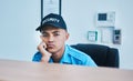 Portrait, surveillance and a bored man security guard sitting at a desk in his office to serve and protect. CCTV, safety