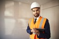 Portrait Of Surveyor In Hard Hat And High Visibility Jacket With Digital Tablet Carrying Out House Inspection