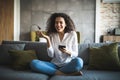 Portrait of a suspicious woman holding phone looking at you sitting on a sofa in the living room of a house Royalty Free Stock Photo