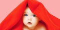 Portrait of sweet baby lying under red towel on pink background Royalty Free Stock Photo