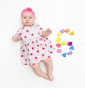 Portrait of a sweet infant baby girl wearing a pink dress and headband bow, isolated on white in studio with number six