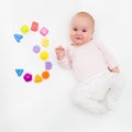 Portrait of a sweet infant baby girl wearing a red dress and bonnet, isolated on white in studio with number tree from