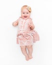 Portrait of a sweet infant wearing a pink dress, headband bow, isolated on white in studio.