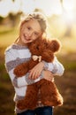 Teddy is her first true love. Portrait of a sweet little girl hugging her teddy bear while playing outside. Royalty Free Stock Photo