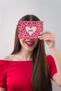 Portrait of a sweet perfect girl smiling at camera with heart shaped paper in her hands. Valentine`s Day or Women`s Day Royalty Free Stock Photo