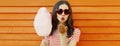 Portrait of sweet young woman blowing her lips sending air kiss with cotton candy wearing red heart shaped sunglasses in amusement Royalty Free Stock Photo