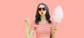 Portrait of sweet young woman blowing her lips sending air kiss with cotton candy wearing red heart shaped sunglasses on pink Royalty Free Stock Photo