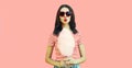 Portrait of sweet young woman blowing her lips sending air kiss with cotton candy wearing red heart shaped sunglasses on pink Royalty Free Stock Photo