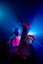 Portrait of talented musician seated, playing trumpet with soft blue-pink stage lights highlighted his silhouette. Royalty Free Stock Photo