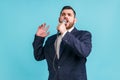 Portrait of talented young adult bearded man wearing official style suit singing songs holding