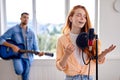 Portrait of talented young caucasian people making modern music, singing in room