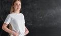 Portrait of a tall smiling female student standing in front of a blackboard in the office. Clean black chalk board. A 25 Royalty Free Stock Photo