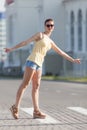 Portrait of tall woman in yellow sleeveless blouse and jeans shorts on street