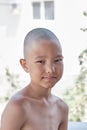 Portrait of a tanned Asian boy with a bald haircut.