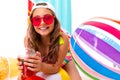 Portrait of a tanned girl drinks juice on the background of inflatable swimming mattresses and balls