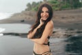 Portrait of tanned smiling girl with closed eyes in swimsuit resting on beach with black sand. Royalty Free Stock Photo