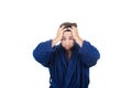 Portrait of tardy young man wears blue bathrobe holding hands to head, unable to wake up in time to get to work, isolated on white