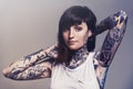 Portrait, tattoo and edgy with a woman in a tank top on a studio gray background for contemporary style. Fashion, body