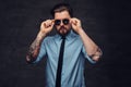 Portrait of a tattooed handsome middle-aged man with beard and hairstyle dressed in a blue shirt and tie, pose with hand Royalty Free Stock Photo